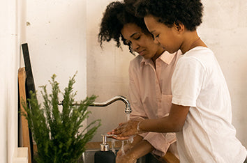 A mother and child wash their hands in a bathroom