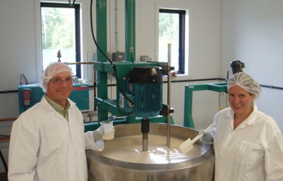 Co-founders of Green Beaver, Alain Menard and Karen Clark stand in front of a metal vat wearing lab coats