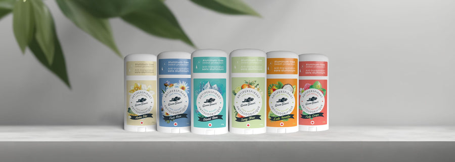 Six Green Beaver aluminum-free antiperspirants sit on a counter, with a plant to the side.