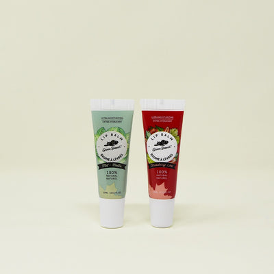 Two tubes of Green Beaver's Mint and Strawberry Lip all-natural lip balm against a plain background.