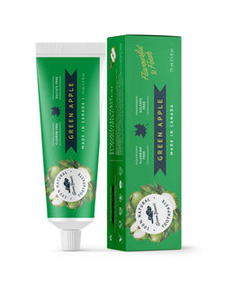 A tube of green apple natural toothpaste from Green Beaver is placed vertically next to its box on a white background.