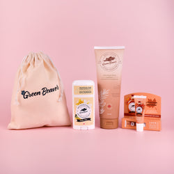 A Green Beaver bundle of Vanilla Bliss Antiperspirant, Coconut Body Lotion, Maple Lip Balm, all with a jute bag and on a pink background.