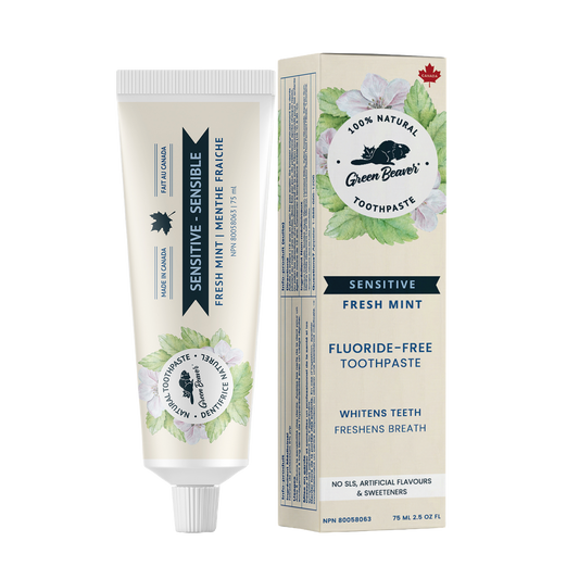 A tube of mint sensitive teeth natural toothpaste from Green Beaver is placed vertically next to its box on a white background.