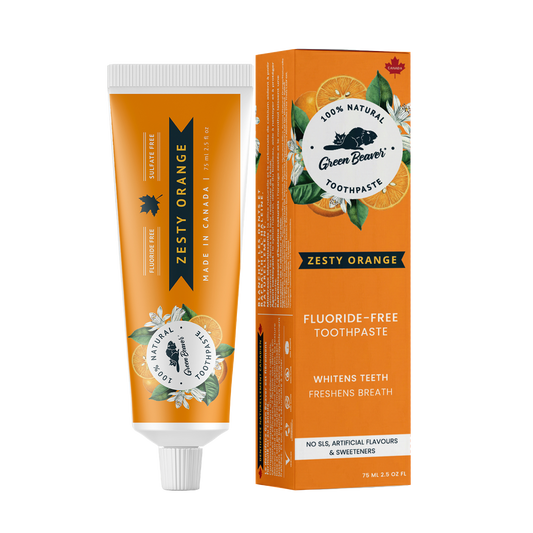 A tube of zesty orange natural toothpaste from Green Beaver is placed vertically next to its box on a white background.