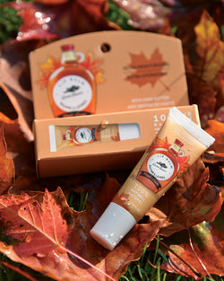 A tube of lip balm is set on top of fall leaves in the grass