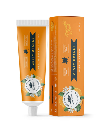 A tube of zesty orange natural toothpaste from Green Beaver is placed vertically next to its box on a white background.